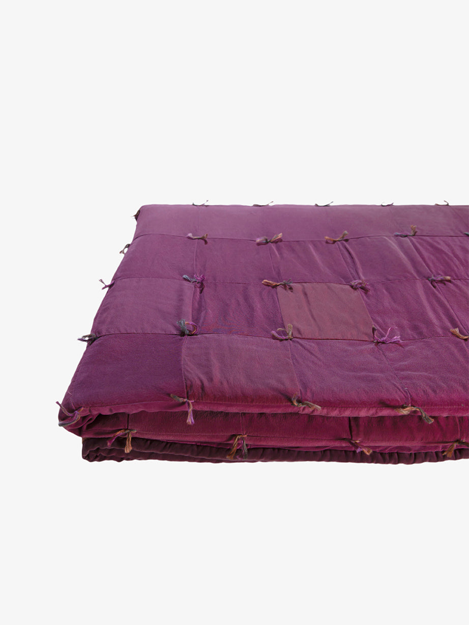 Folded view of Lily Raskind Smoke Brush hand-dyed silk blanket showing quilt thickness and tied patchwork detail.
